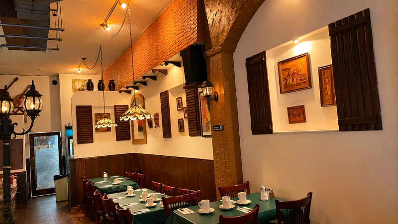 Dining room with a brick archway, stained-glass pendant lamps, wooden shutters and green tablecloths