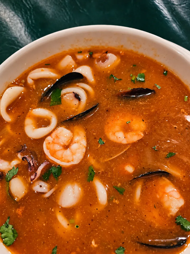 Bowl of red seafood soup with shrimp, calamari rings and mussels